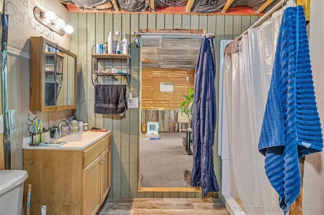 bathroom with toilet, wood walls, and vanity