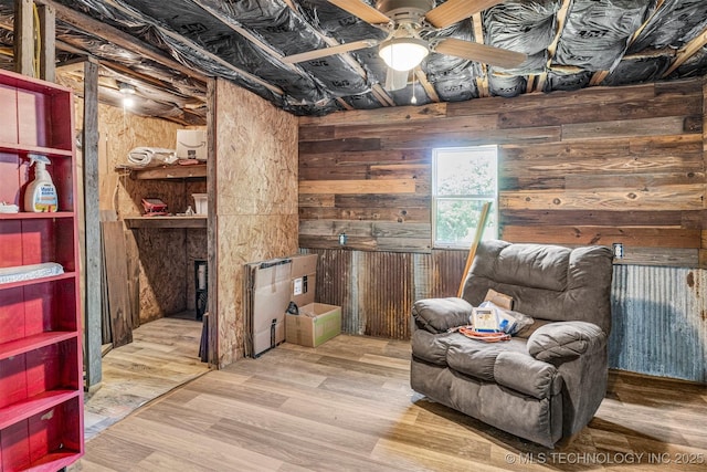 sitting room featuring wood walls, ceiling fan, and wood finished floors