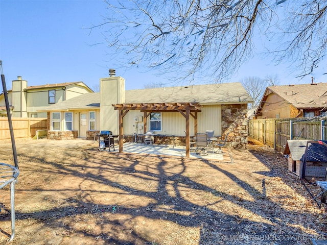 back of house with a patio, a chimney, a pergola, stone siding, and a fenced backyard