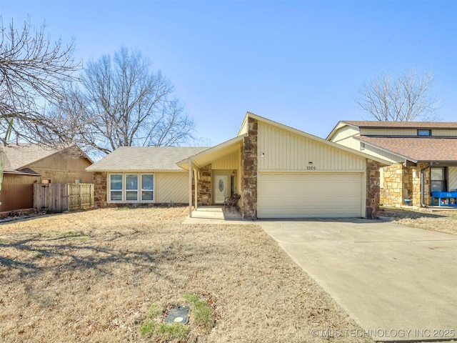 mid-century inspired home with an attached garage, stone siding, fence, and concrete driveway