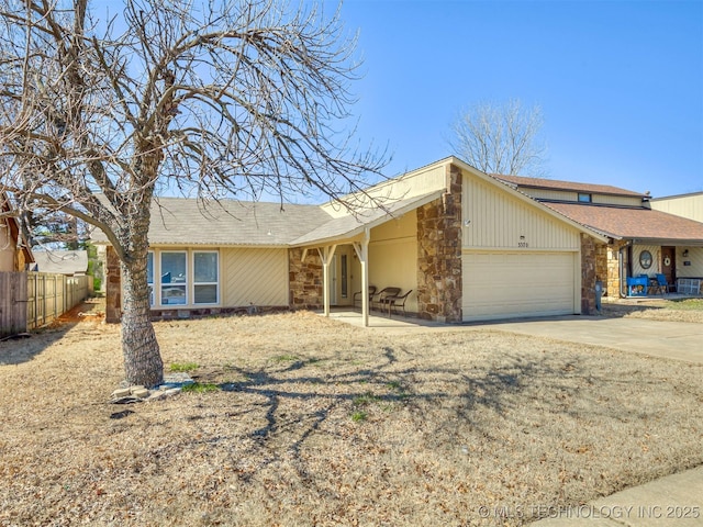 view of front of property with a garage, concrete driveway, fence, and stone siding