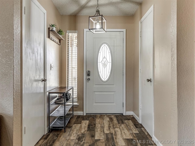 foyer with dark wood finished floors, a textured ceiling, and baseboards