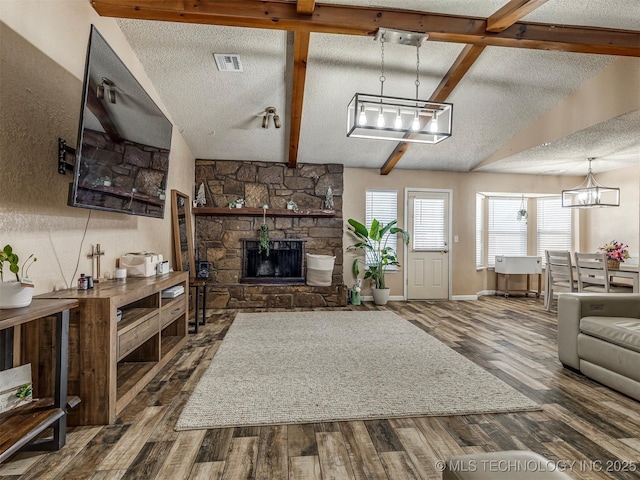 living room featuring vaulted ceiling with beams, visible vents, a textured ceiling, and wood finished floors