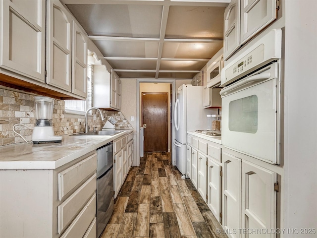 kitchen featuring tasteful backsplash, dark wood-type flooring, oven, light countertops, and a sink