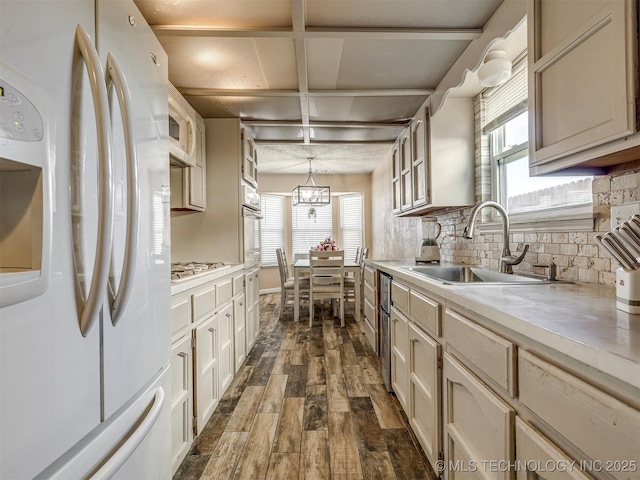 kitchen with white appliances, dark wood finished floors, a sink, light countertops, and backsplash