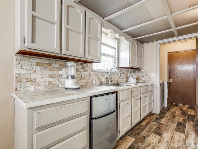 kitchen featuring light countertops, backsplash, a sink, and dark wood-style flooring