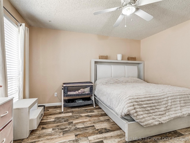 bedroom featuring multiple windows, a textured ceiling, and wood finished floors