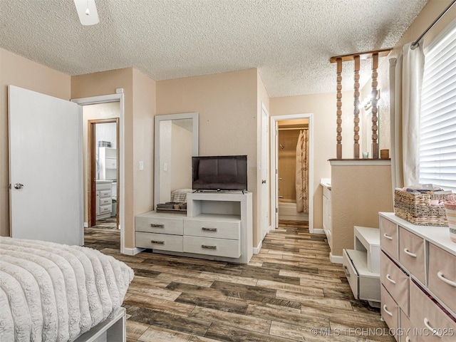 bedroom with multiple windows, a textured ceiling, baseboards, and wood finished floors