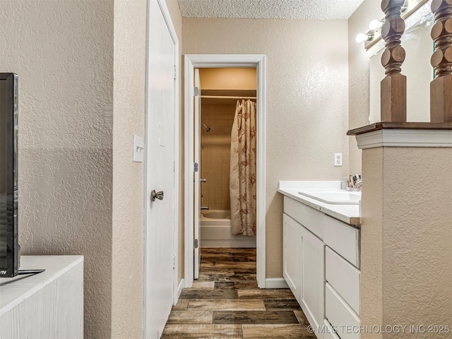 bathroom featuring shower / tub combo, a textured wall, wood finished floors, a textured ceiling, and vanity