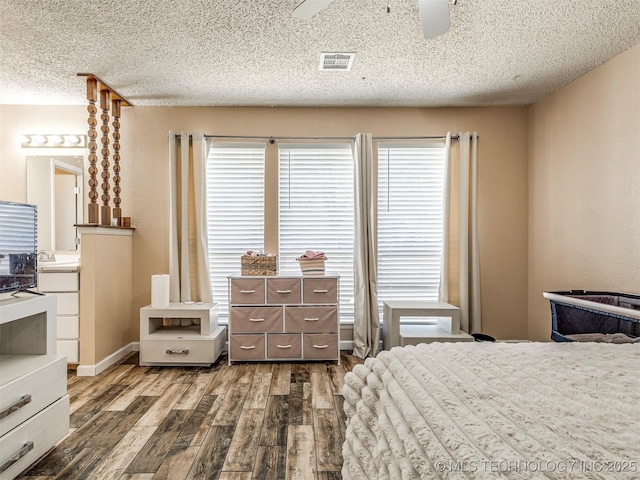 bedroom with visible vents, a ceiling fan, connected bathroom, dark wood-type flooring, and a textured ceiling