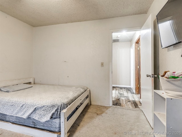 bedroom featuring carpet, visible vents, and a textured ceiling