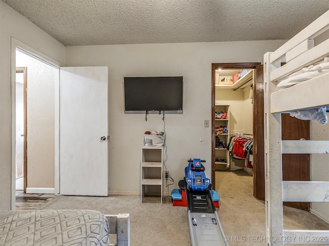 bedroom featuring a textured ceiling, a spacious closet, a closet, and carpet flooring