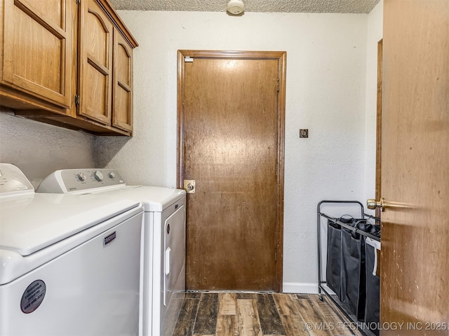 laundry room featuring cabinet space, washer and clothes dryer, dark wood finished floors, and a textured wall