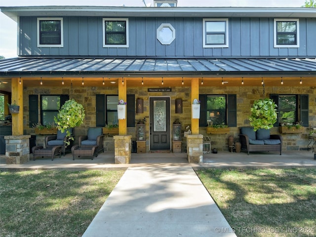 view of front of property featuring stone siding, a standing seam roof, a patio area, and board and batten siding