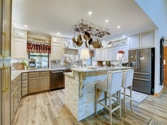 kitchen featuring stainless steel appliances, light wood-type flooring, a kitchen island, and decorative backsplash