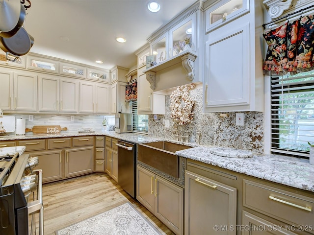 kitchen featuring light wood-style floors, decorative backsplash, a sink, and gas stove