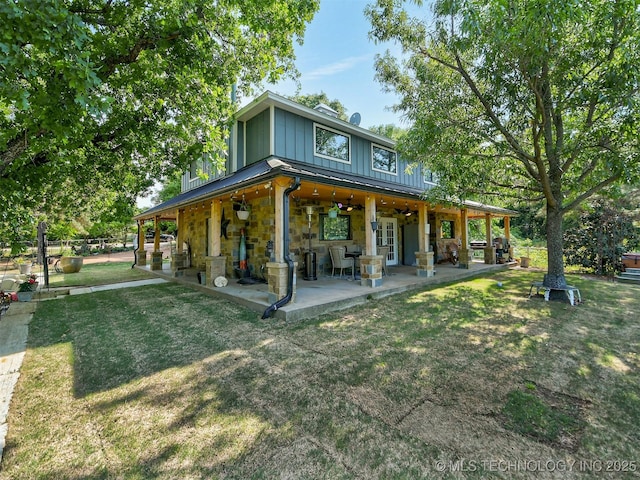 back of house featuring a patio, board and batten siding, a ceiling fan, a standing seam roof, and stone siding