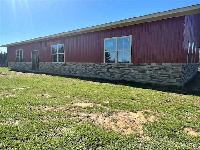 view of side of property with stone siding and a lawn