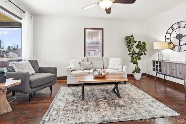 living room with dark wood finished floors, a ceiling fan, and baseboards