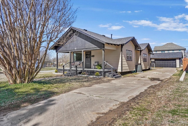 bungalow-style house with a shingled roof, a detached garage, a porch, and an outdoor structure