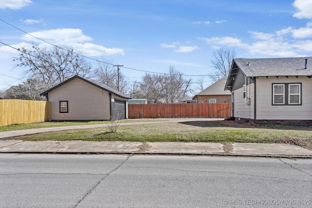 view of side of home with a garage, driveway, fence, and an outbuilding
