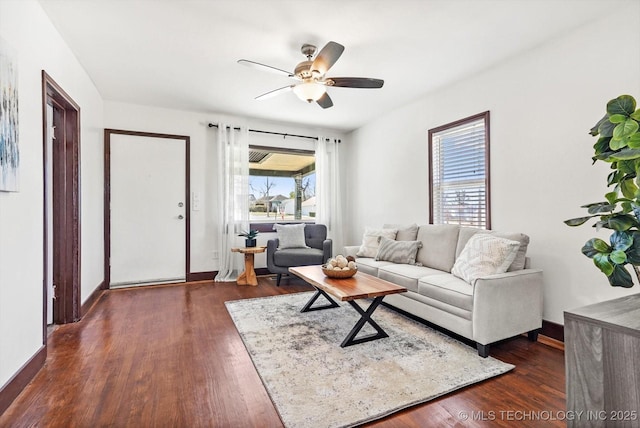 living area with baseboards, a ceiling fan, and dark wood-type flooring