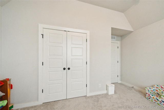 unfurnished bedroom featuring lofted ceiling, a closet, carpet flooring, and baseboards