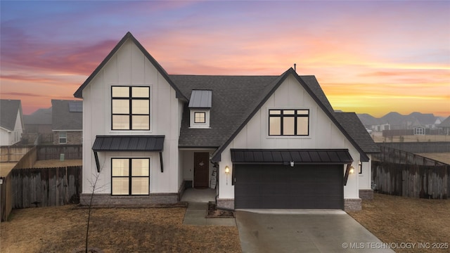 modern farmhouse style home featuring driveway, roof with shingles, a standing seam roof, fence, and board and batten siding