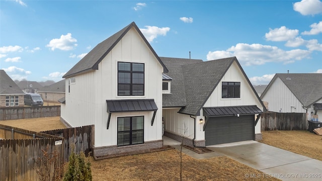 modern farmhouse with a shingled roof, fence, driveway, board and batten siding, and a standing seam roof