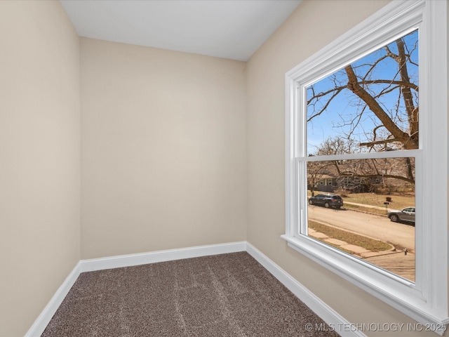 empty room with dark colored carpet and baseboards