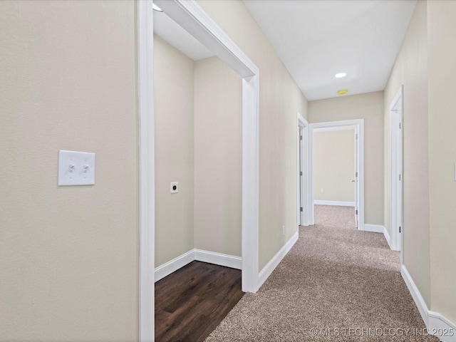 hallway with dark carpet and baseboards