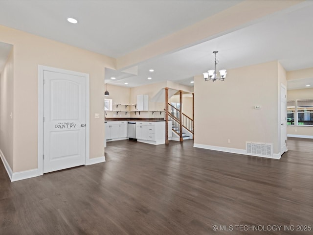 unfurnished living room featuring baseboards, visible vents, dark wood-type flooring, an inviting chandelier, and recessed lighting