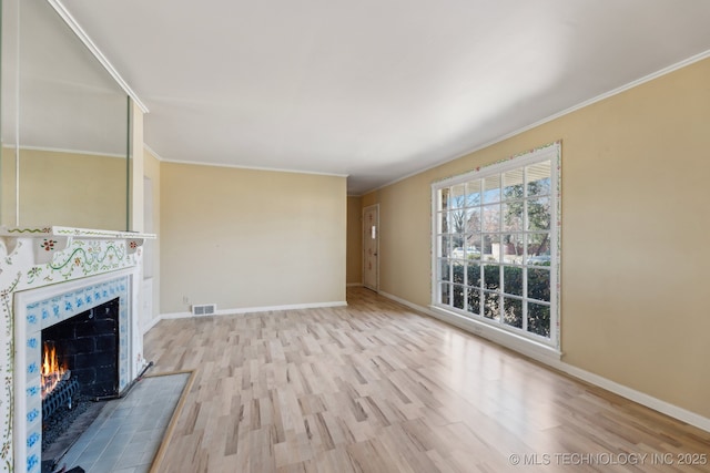 unfurnished living room with a fireplace, baseboards, wood finished floors, and ornamental molding