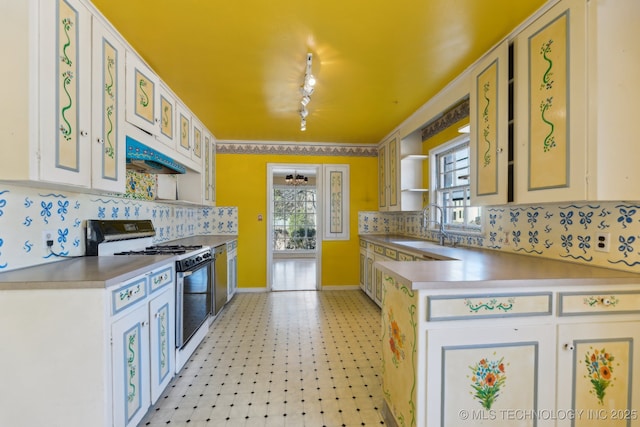 kitchen featuring a healthy amount of sunlight, white range with gas cooktop, under cabinet range hood, and a sink