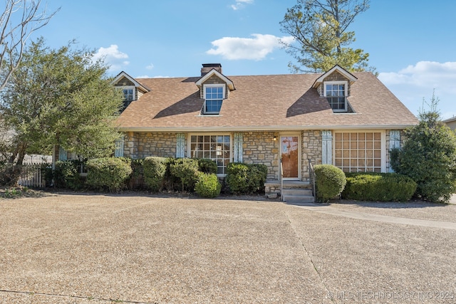 cape cod-style house featuring roof with shingles