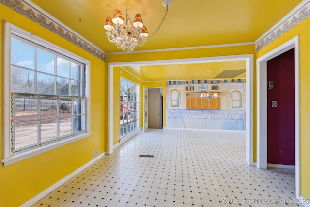 corridor featuring an inviting chandelier, baseboards, and crown molding