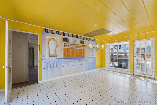 spare room with baseboards, a notable chandelier, and tile patterned floors