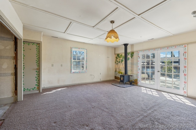 carpeted spare room with french doors and a wood stove