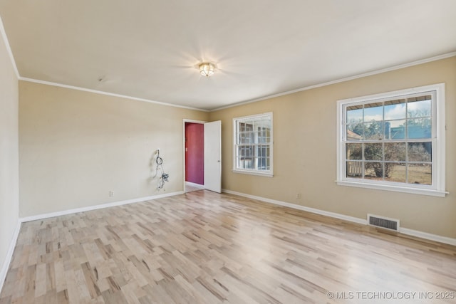 empty room with crown molding, wood finished floors, visible vents, and baseboards