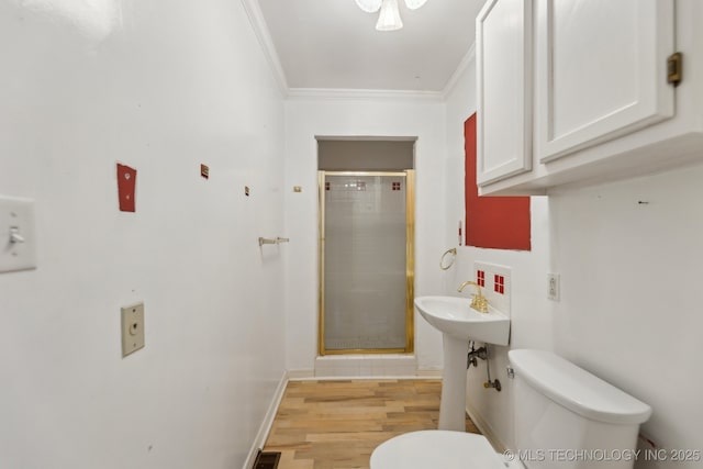 full bathroom with crown molding, toilet, a stall shower, wood finished floors, and baseboards