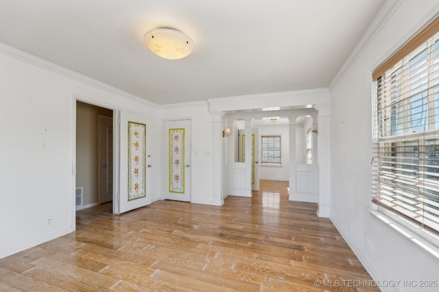 unfurnished room with a wealth of natural light, crown molding, and light wood-style flooring