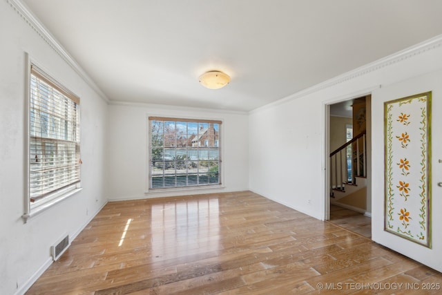 unfurnished room with visible vents, crown molding, stairway, and wood finished floors