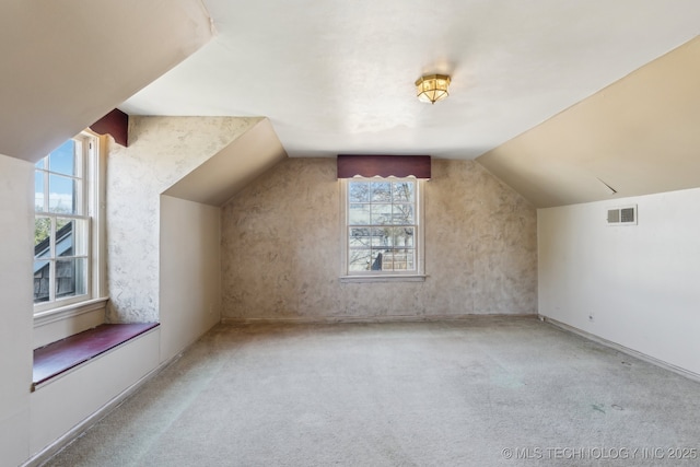 bonus room featuring carpet, visible vents, and vaulted ceiling