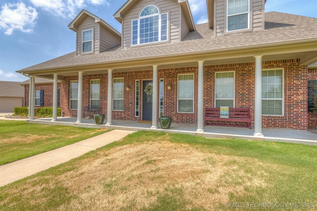 view of front of house featuring covered porch, brick siding, a front lawn, and a shingled roof