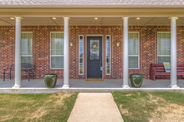 property entrance with covered porch and brick siding