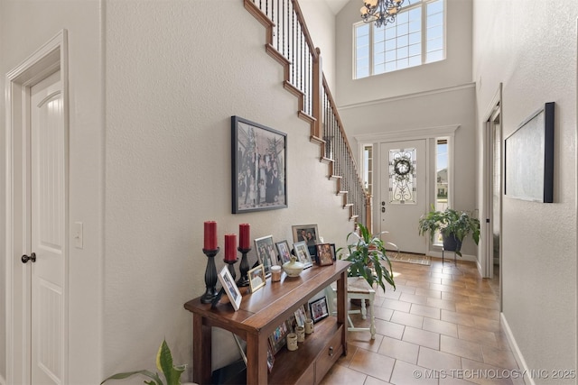 entrance foyer with light tile patterned floors, a high ceiling, baseboards, stairway, and an inviting chandelier