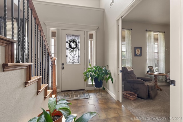 carpeted entrance foyer with baseboards, stairs, and visible vents