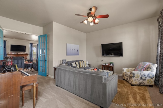 living area with baseboards, a fireplace, a ceiling fan, and light colored carpet