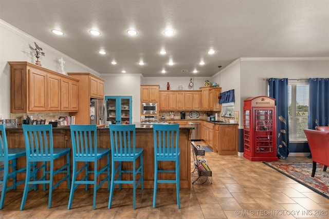 kitchen featuring appliances with stainless steel finishes, a breakfast bar, a peninsula, and decorative backsplash