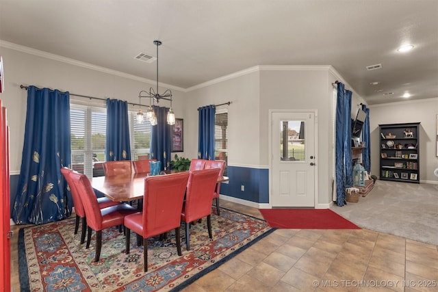 carpeted dining space featuring ornamental molding, visible vents, and a notable chandelier